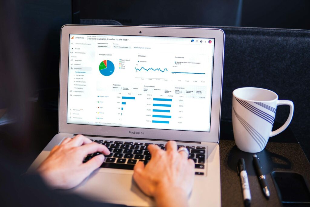 Hand working on a laptop with a white cup on the side