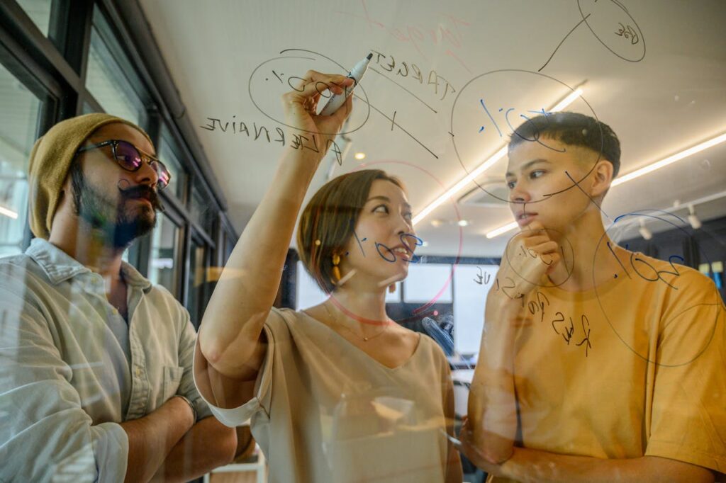 3 Co-workers discussing infront of a clear board